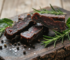 Protein-Fleischriegel aus Schweizer Bio-Rind auf rustikalem Holzbrett mit Rosmarin
